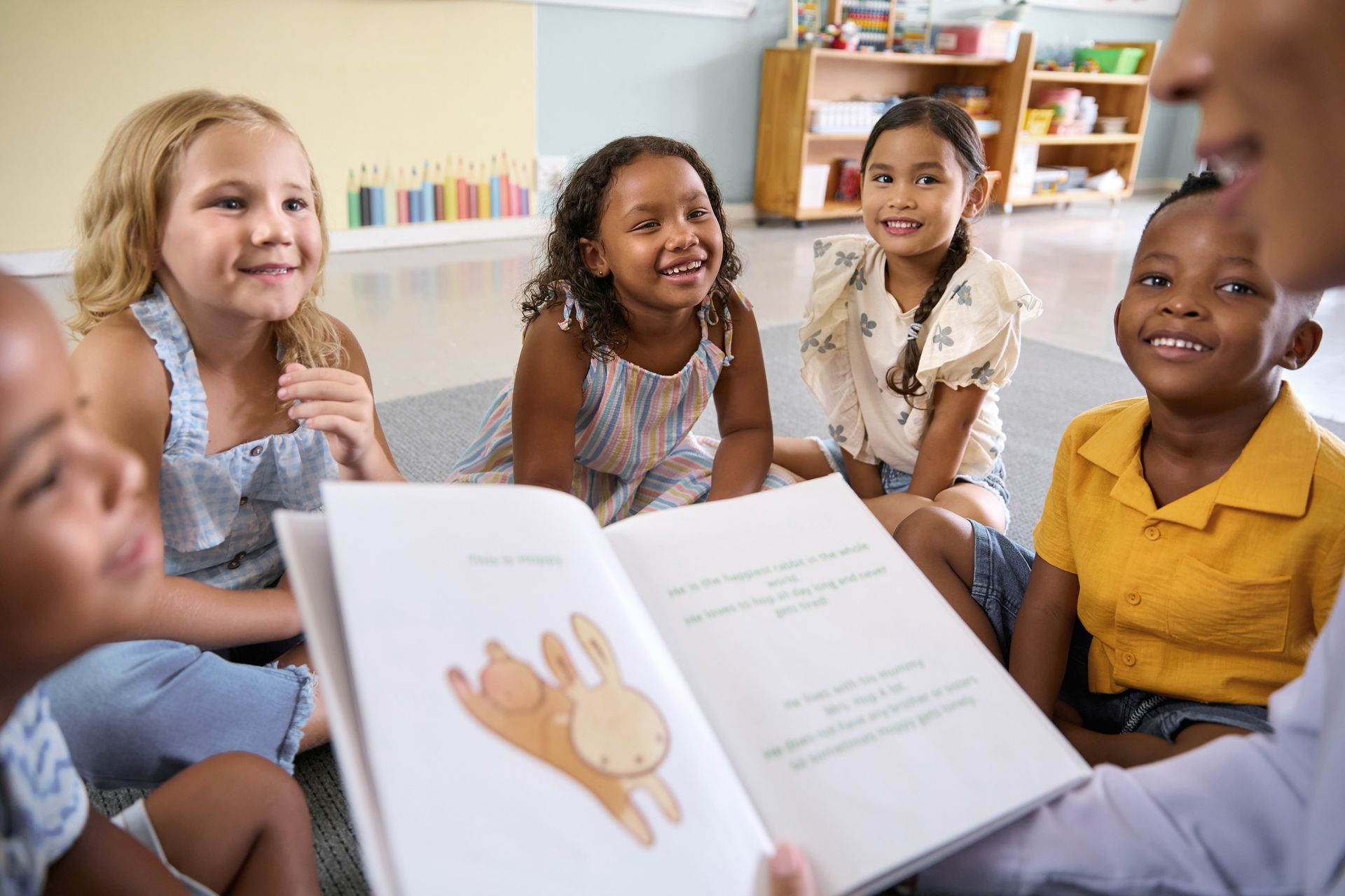 Diverse kindergarteners on a classroom carpet listening to a story.