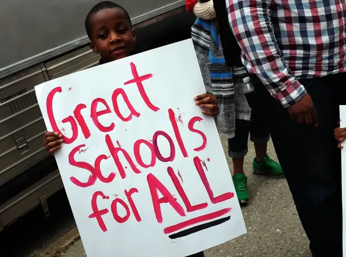 Child holds a sign "Great Schools for ALL."