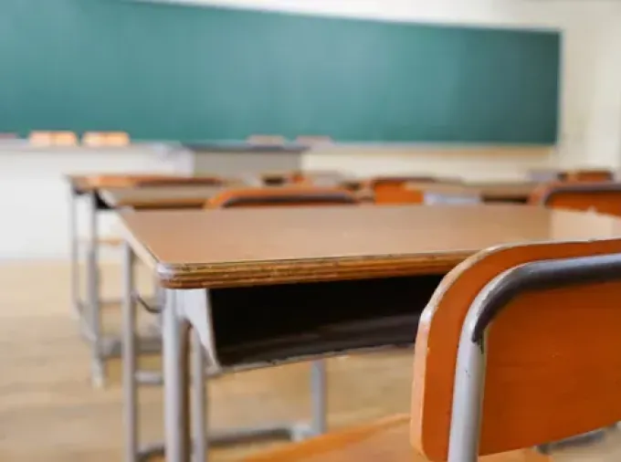 Empty classroom desks and chairs, green chalkboard.